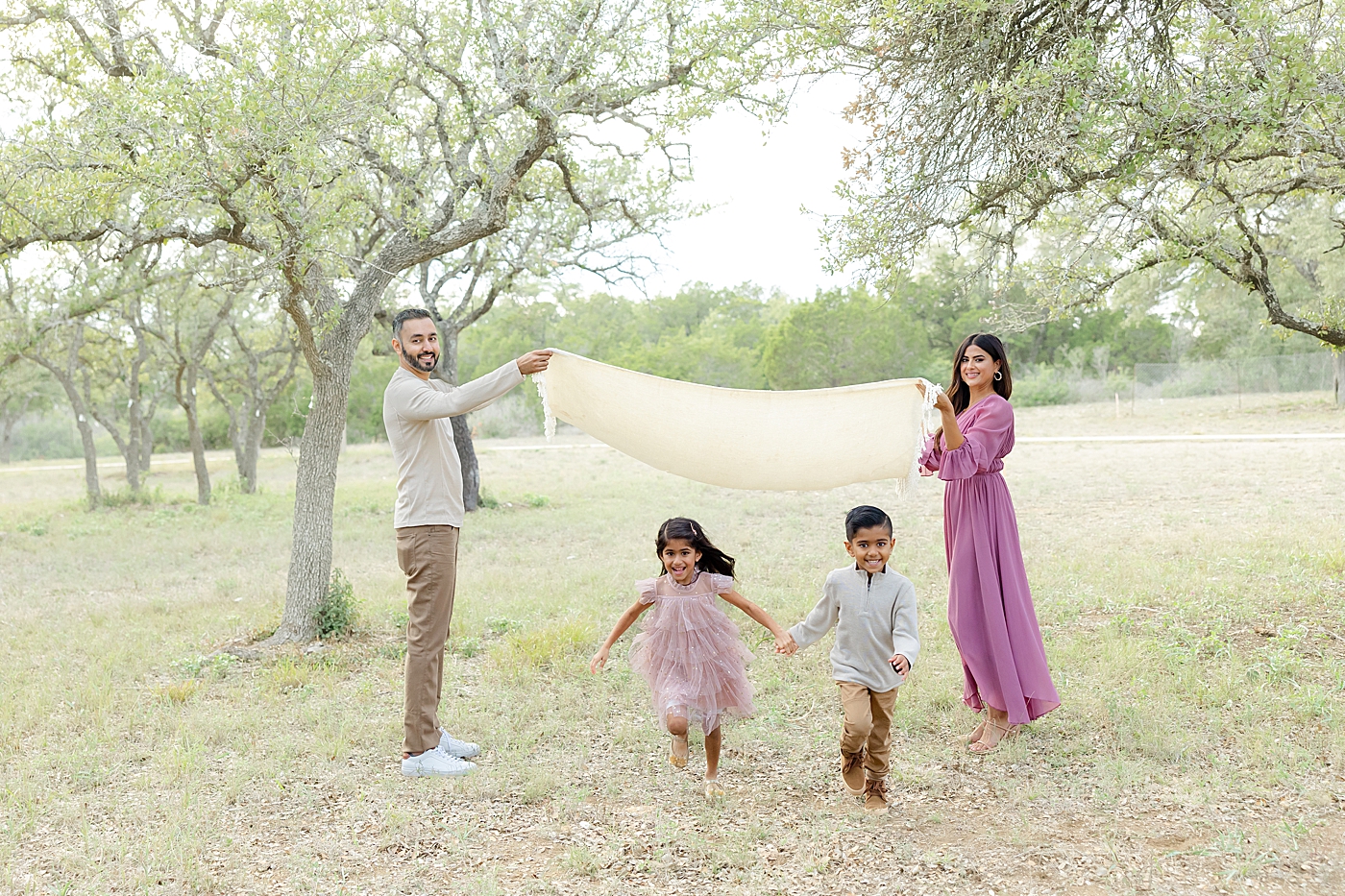 Mom and dad playing with their kids in the park | Image by Sana Ahmed Photography