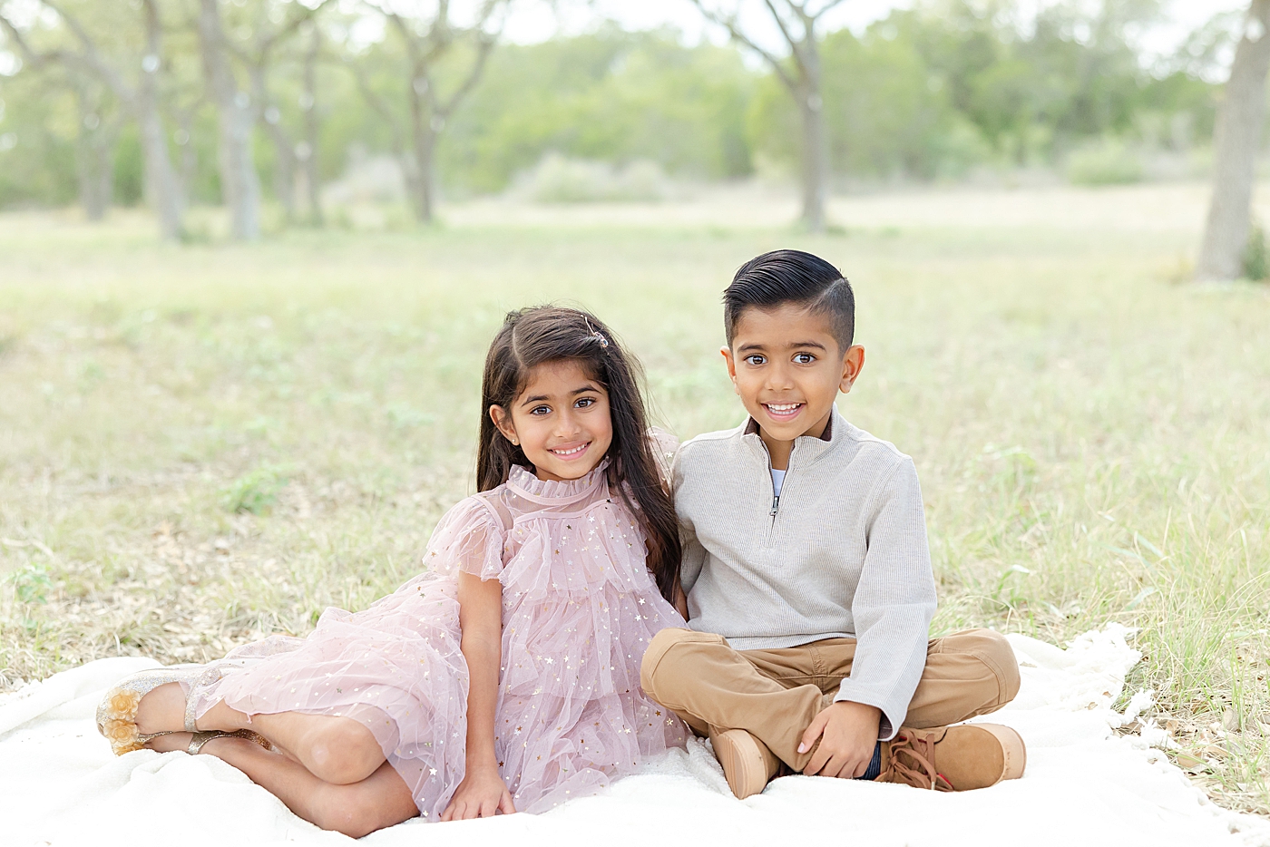 Little boy and girl sitting on a blanket during their Field Family Session | Image by Sana Ahmed Photography