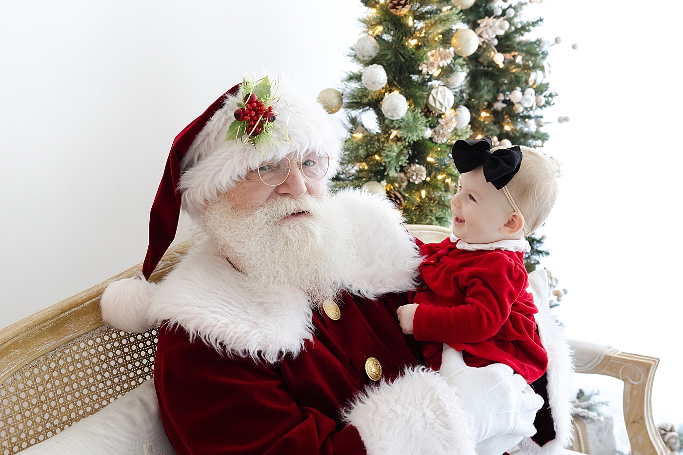 Santa holding a baby girl in a red dress | Image by Sana Ahmed Photography