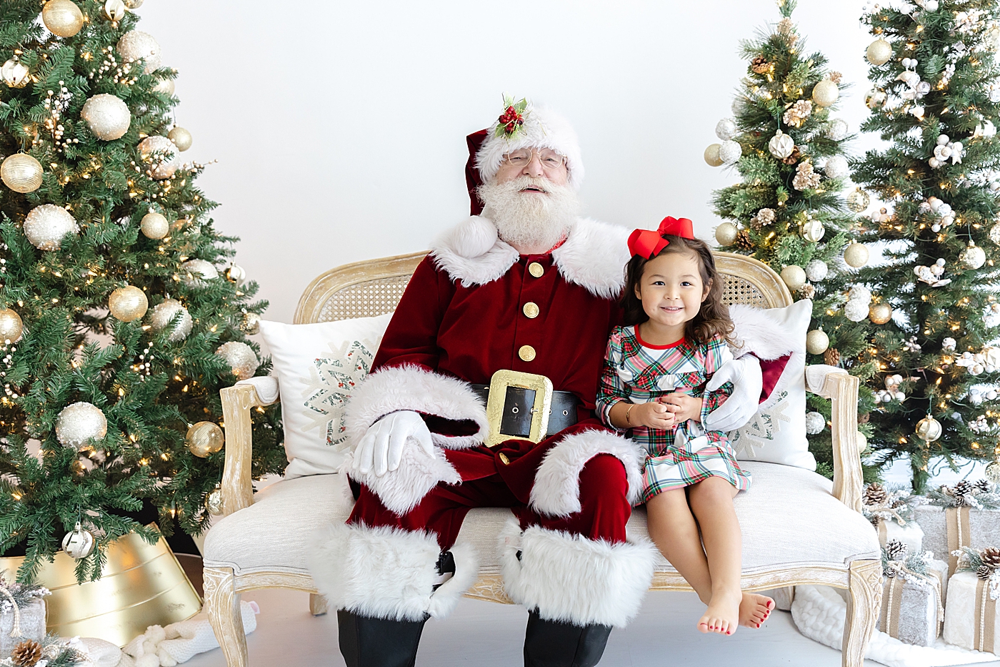 Little girl sitting on a couch with Santa during Santa mini sessions in Austin | Image by Sana Ahmed Photography