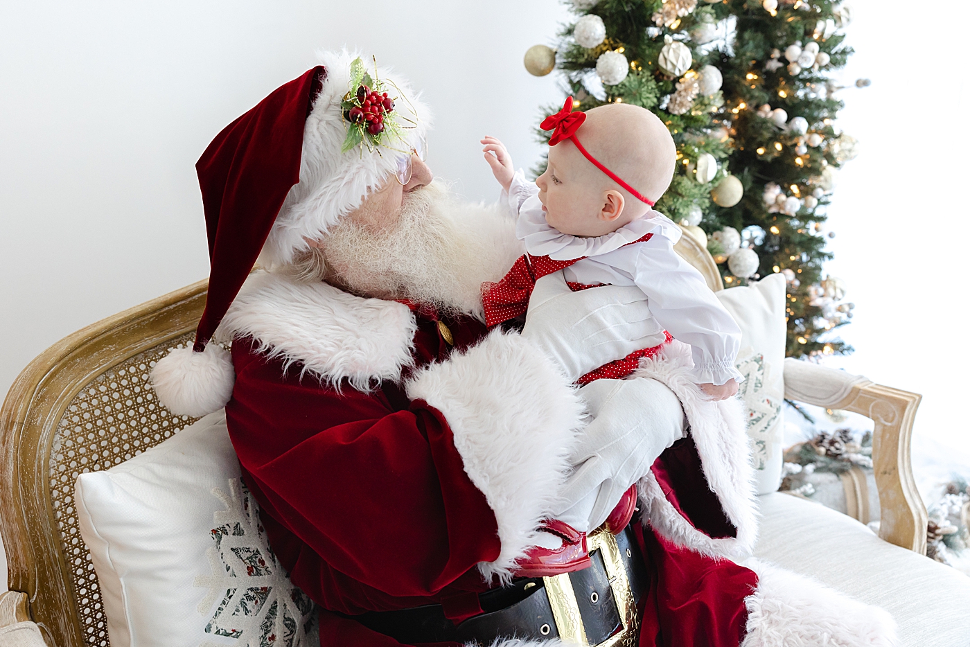 Santa holding a baby girl wearing a red bow | Image by Sana Ahmed Photography