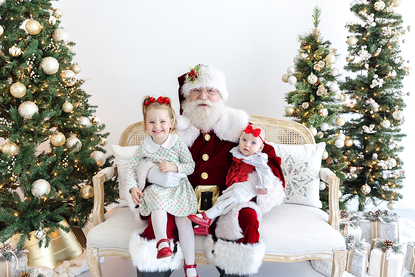 Two sisters sitting on a couch with Santa during Santa mini sessions in Austin | Image by Sana Ahmed Photography