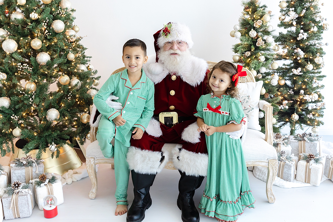 Two little kids in matching green pajamas sitting with Santa | Image by Sana Ahmed