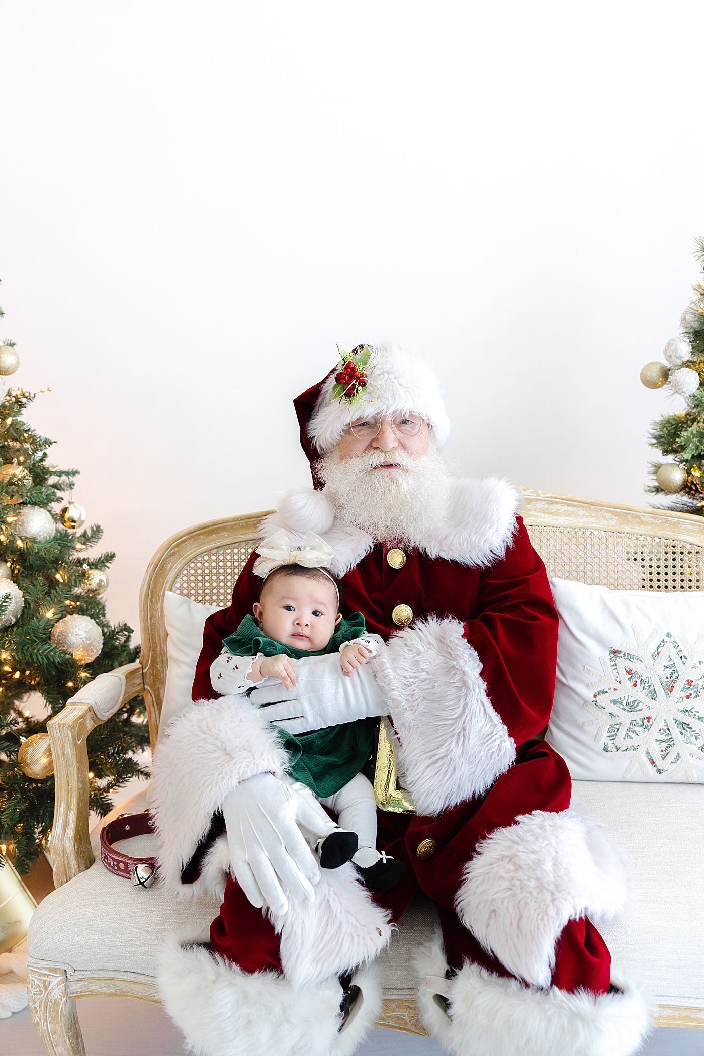 Santa holding a baby girl in green during Santa mini sessions in Austin | Image by Sana Ahmed Photography