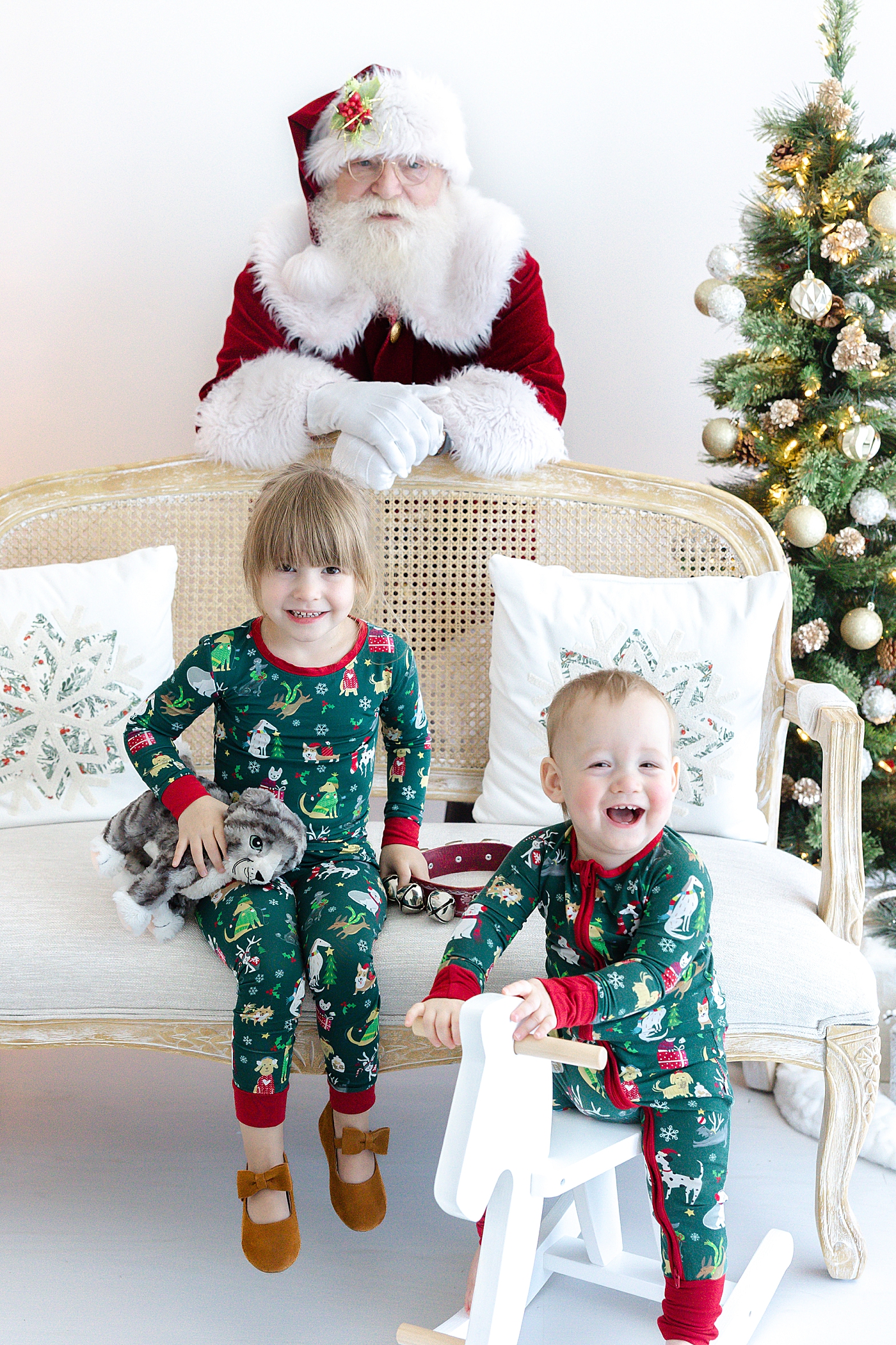 Brother and sister sitting on a couch during Santa mini sessions in Austin | Image by Sana Ahmed Photography