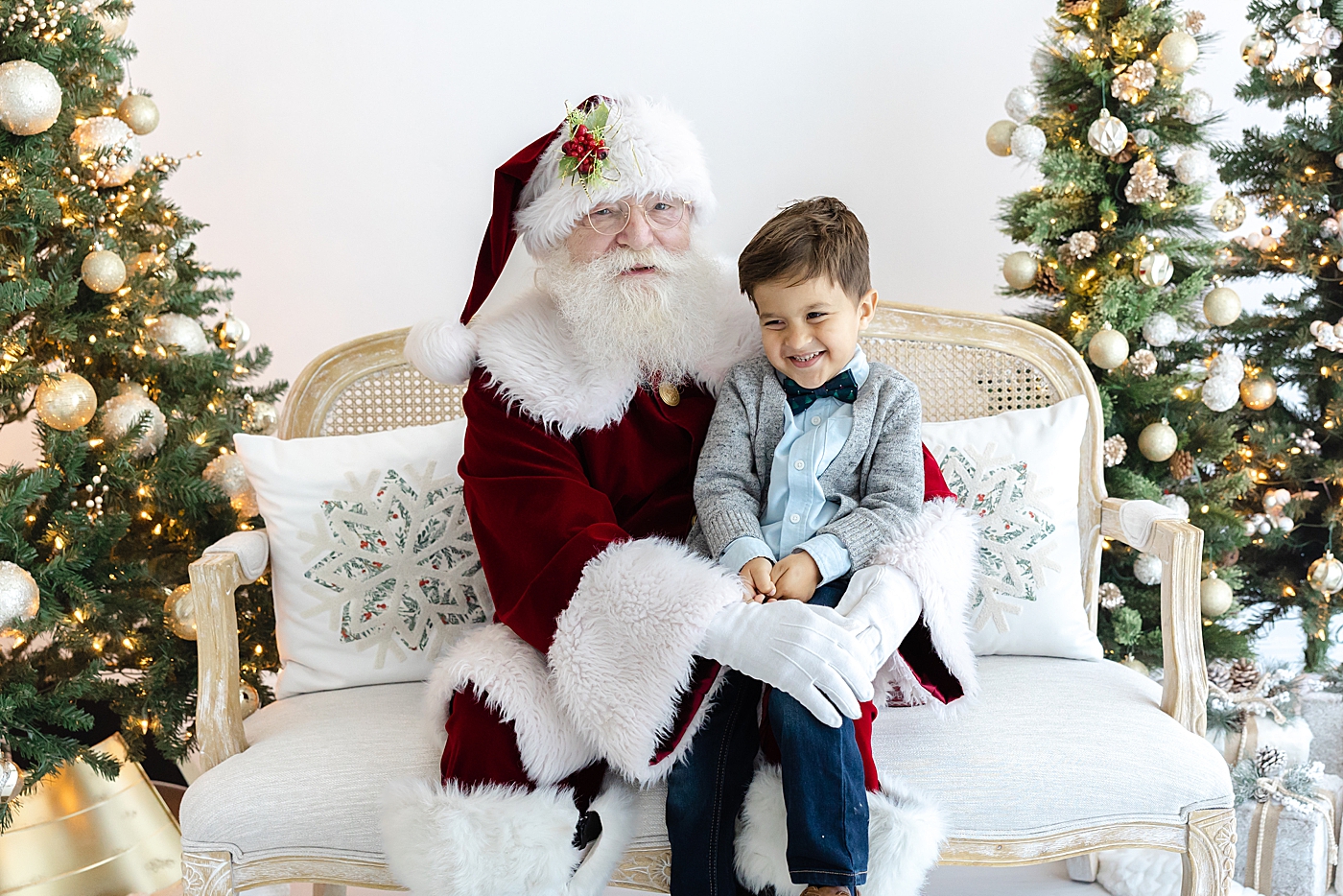 Little boy sitting on Santas lap on a sofa during Santa mini sessions in Austin | Image by Sana Ahmed Photography