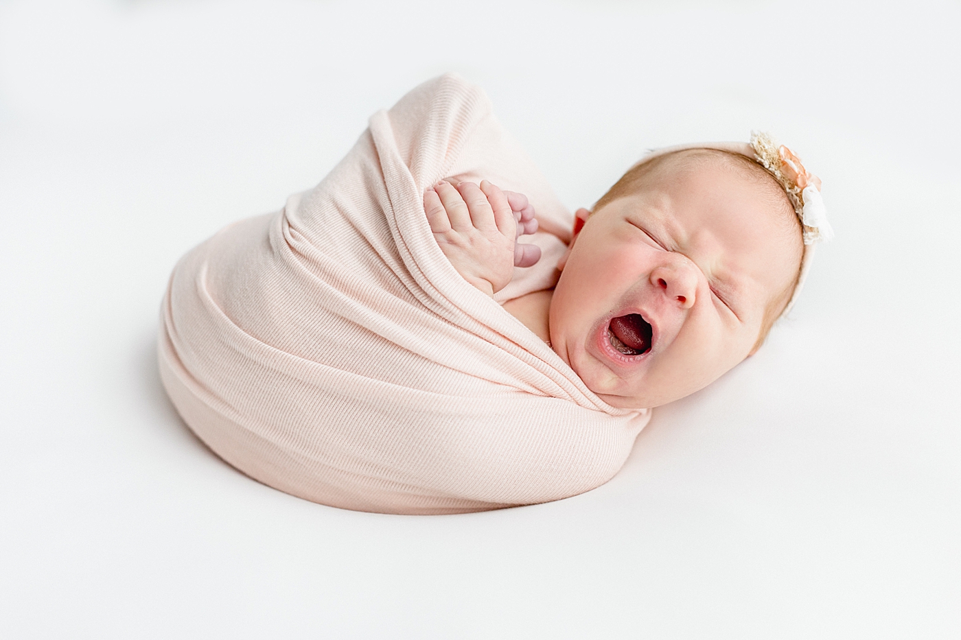Baby girl in a pink swaddle yawning during her One Year Milestone Collection | Image by Sana Ahmed Photography