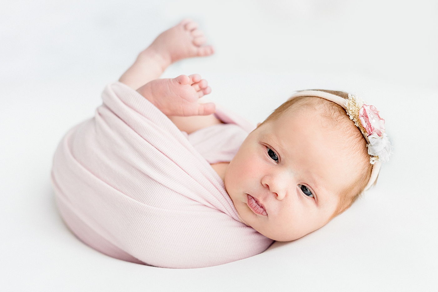 Baby girl in a pink swaddle during her One Year Milestone Collection | Image by Sana Ahmed Photography
