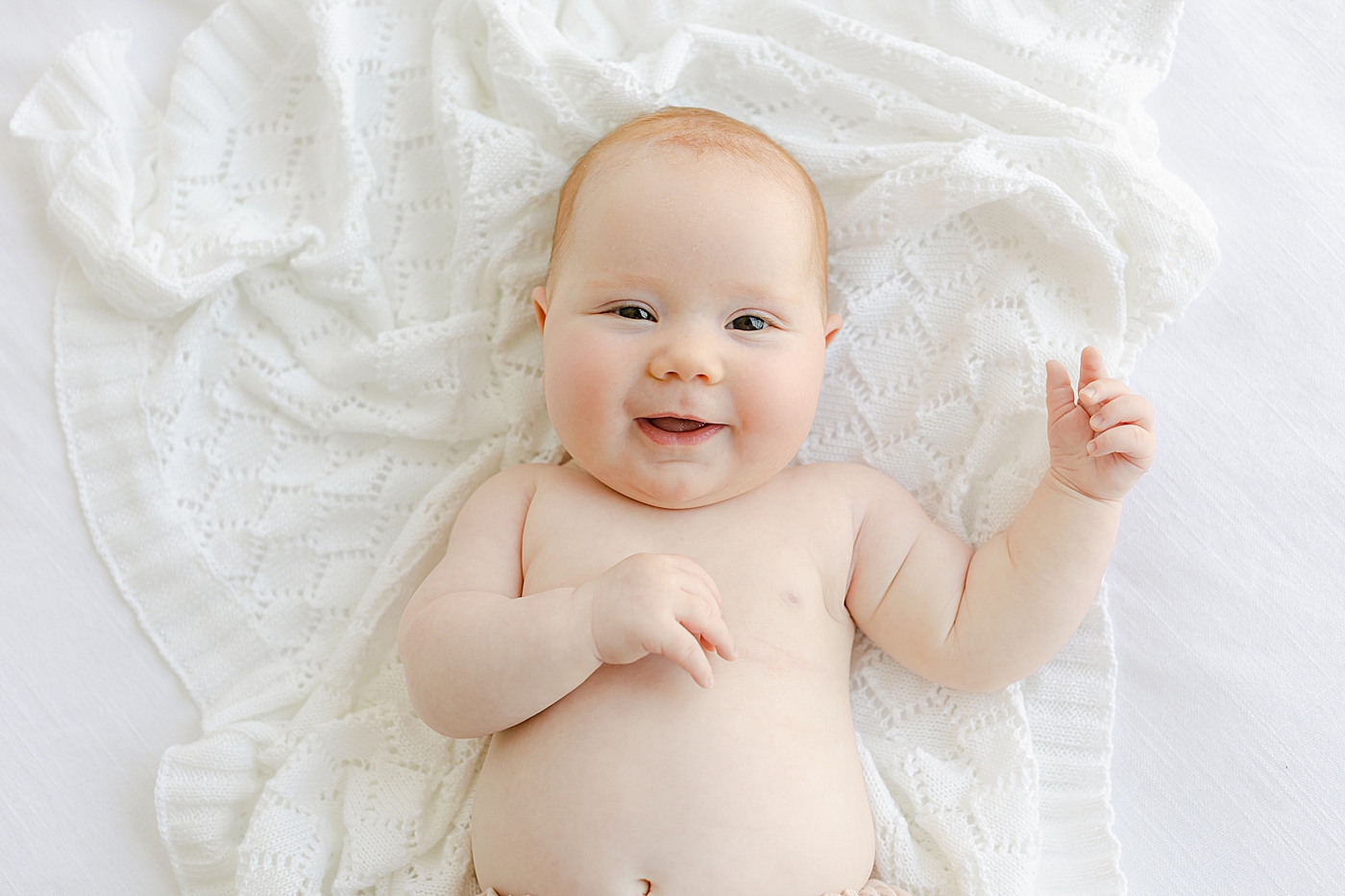 Baby girl smiling on a white blanket | Image by Sana Ahmed Photography