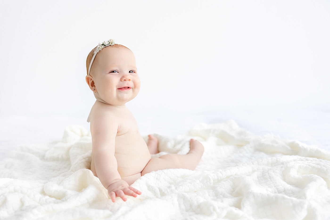 Baby girl sitting on a white blanket | Image by Sana Ahmed Photography
