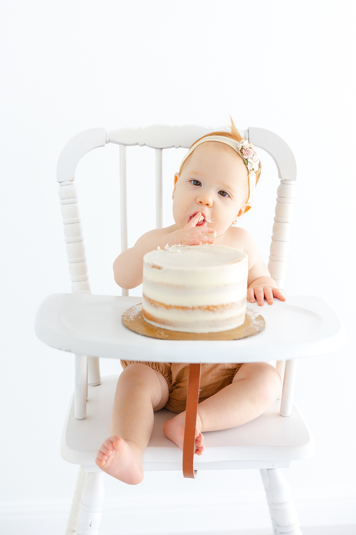 Baby girl eating cake during her One Year Milestone Collection | Image by Sana Ahmed Photography