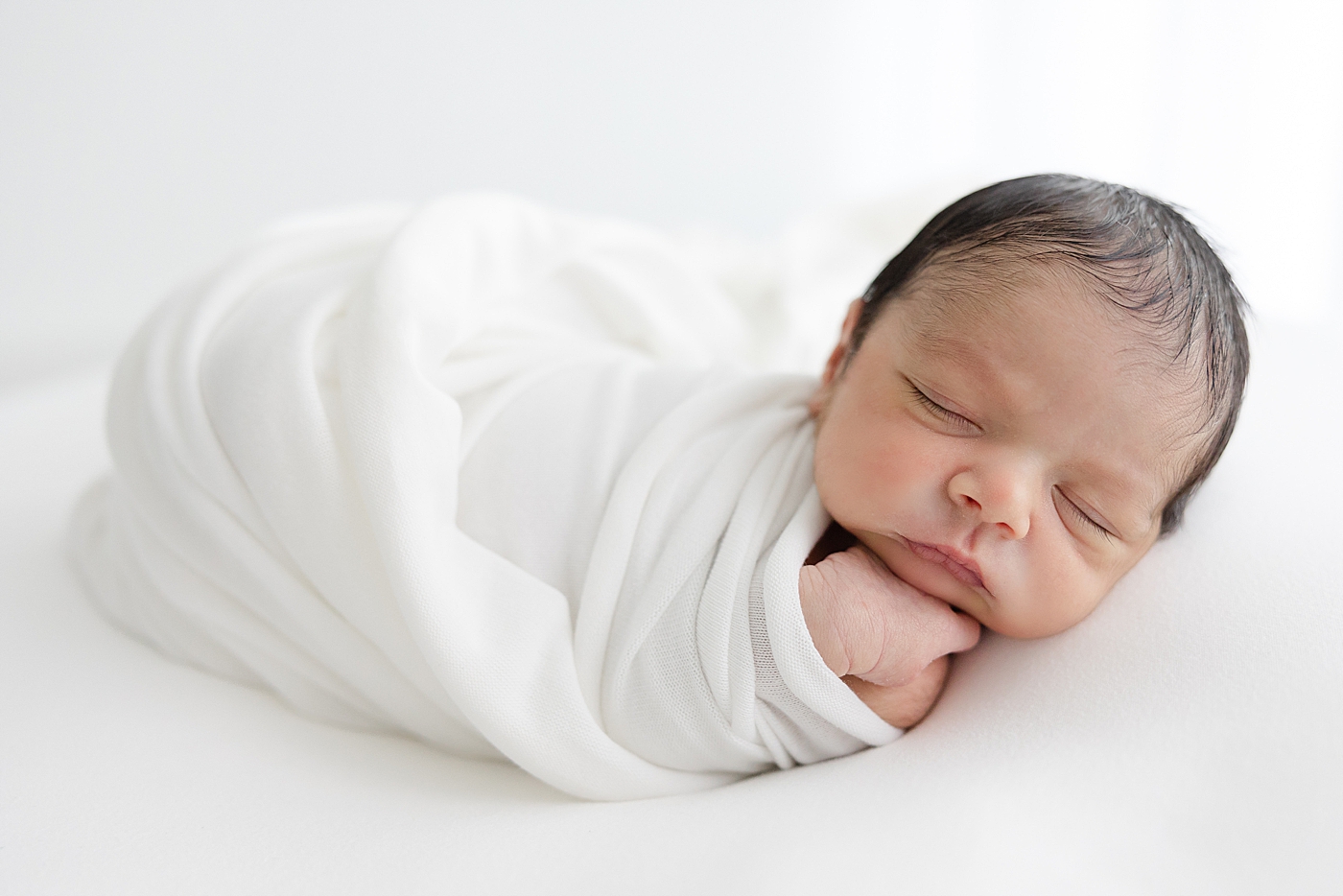Newborn baby wrapped in a white swaddle | Image by Sana Ahmed Photography 