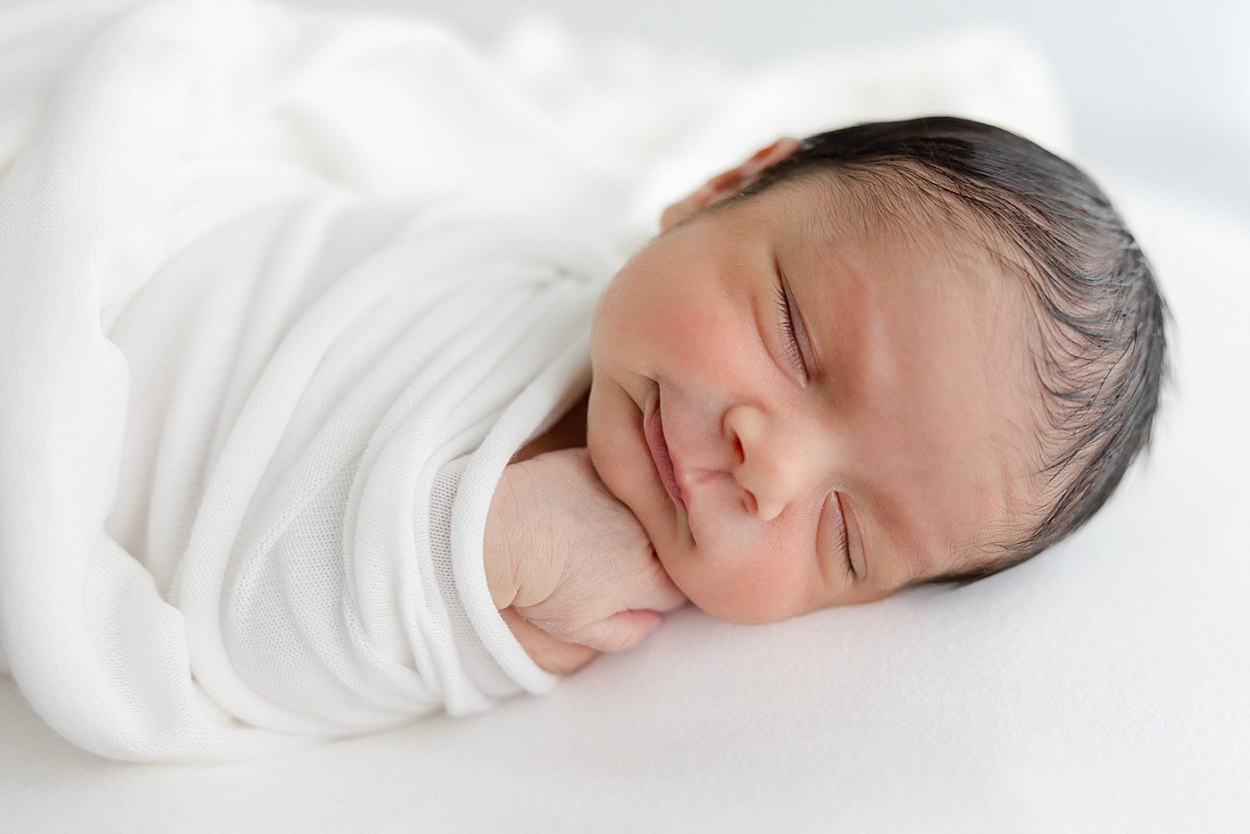 Sleeping baby in a white swaddle during his Studio Newborn Session in Austin | Image by Sana Ahmed Photography 