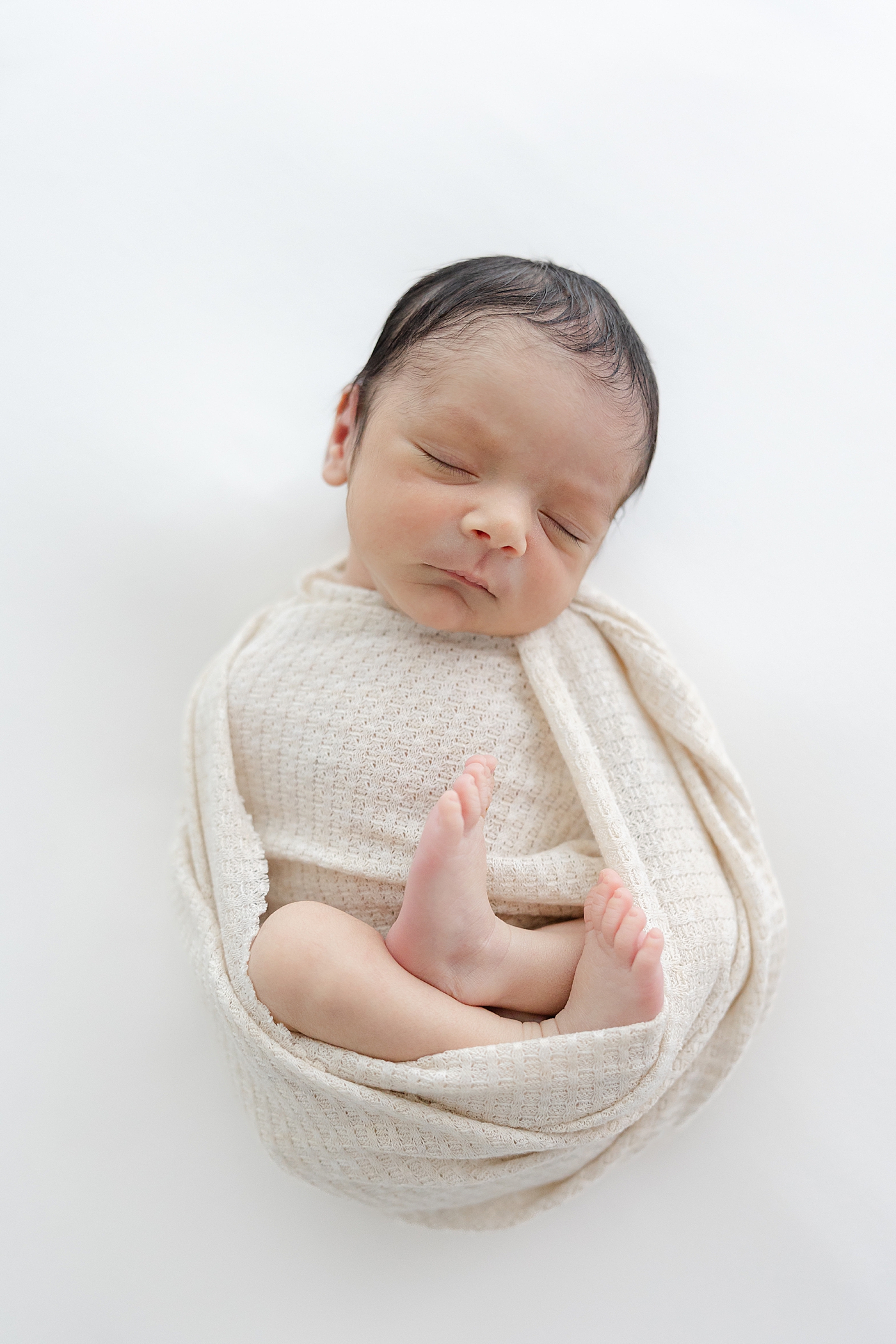 Sleeping newborn baby wrapped in a white swaddle | Image by Sana Ahmed Photography 
