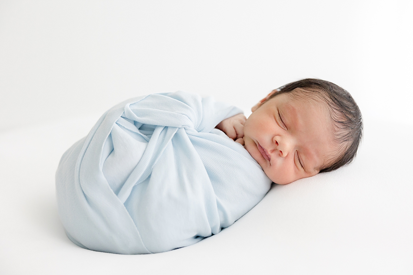 Sleeping newborn wrapped in a swaddle during his Studio Newborn Session in Austin | Image by Sana Ahmed Photography 