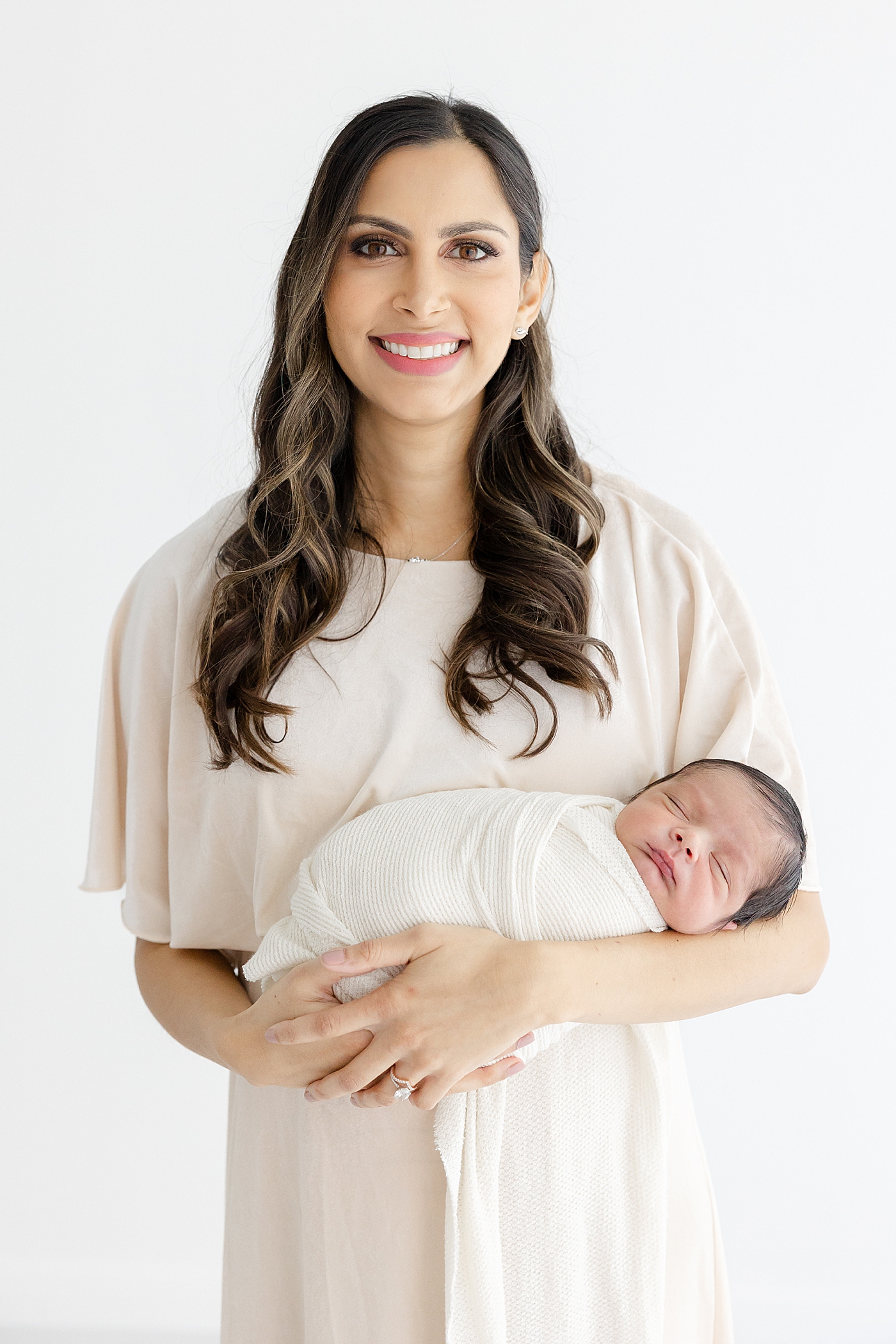 Mom holding her sleeping baby during their Studio Newborn Session in Austin | Image by Sana Ahmed Photography 
