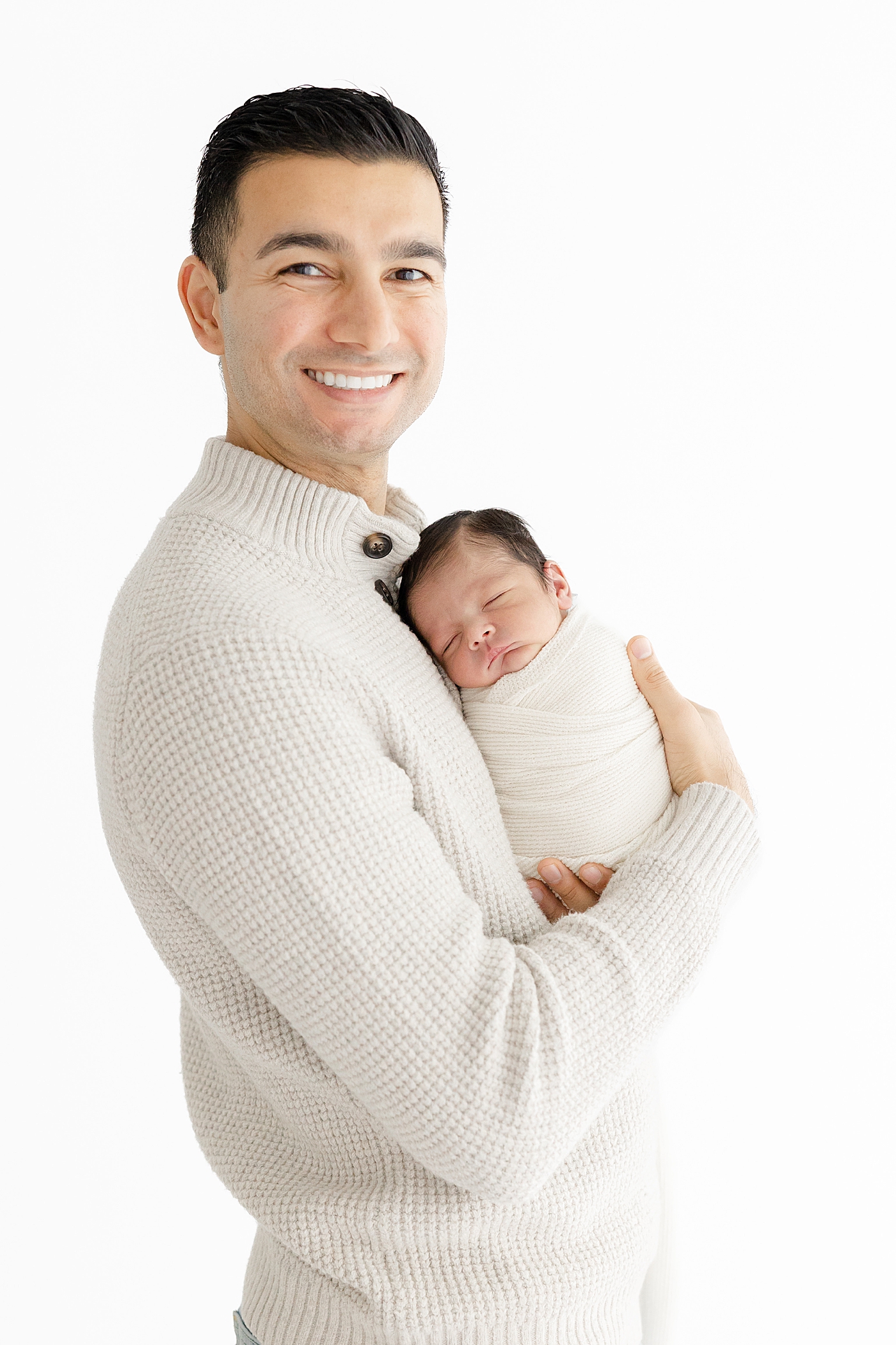 Dad holding his newborn baby during their Studio Newborn Session in Austin | Image by Sana Ahmed Photography 