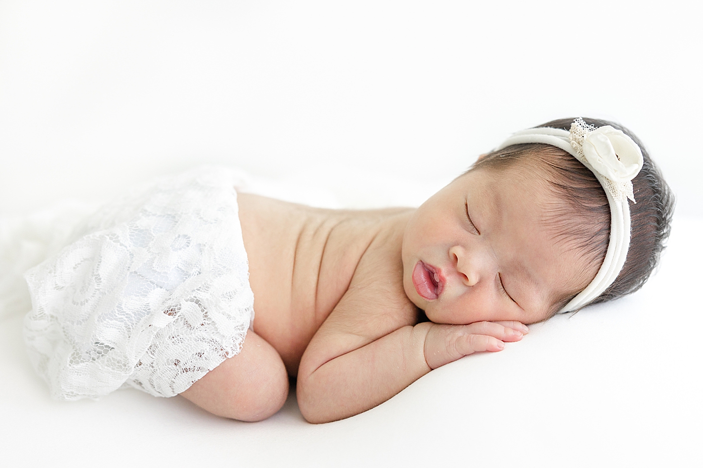 Sleeping newborn in lace bloomers and white headband | Image by Sana Ahmed