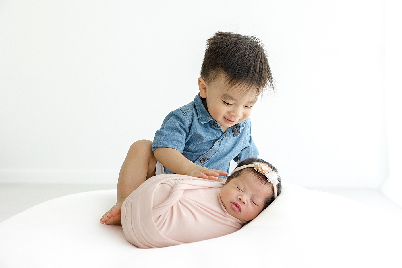 Big brother in blue sitting with his newborn baby sister | Image by Sana Ahmed