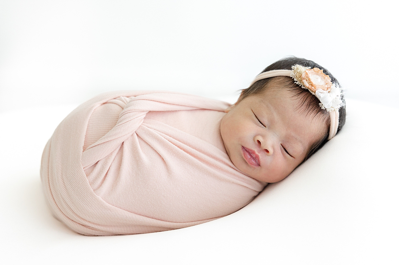 Newborn baby wrapped in a pink swaddle during her Newborn sessions with siblings | Image by Sana Ahmed