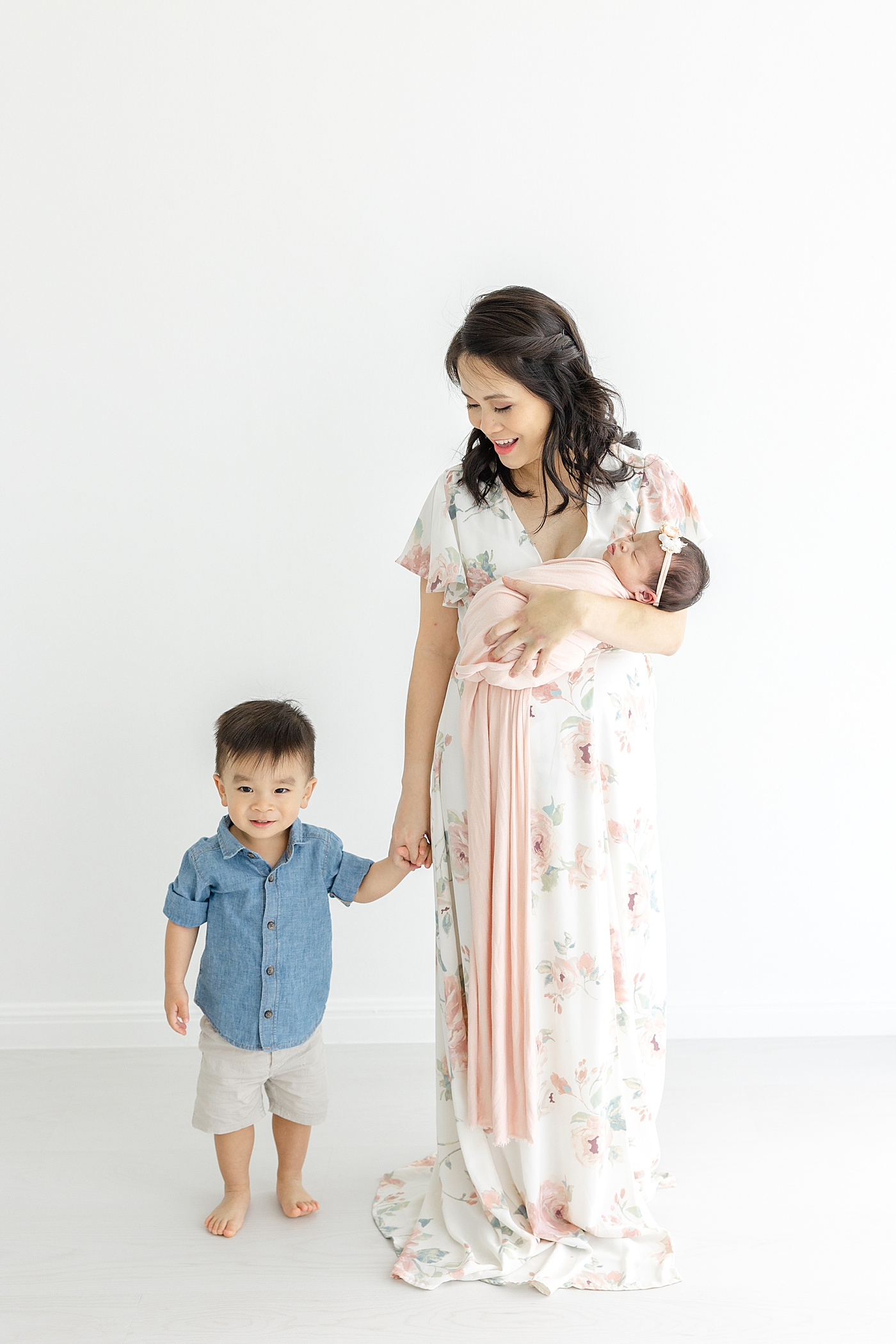 Mom holding her little boys hand and holding her newborn during her Newborn sessions with siblings | Image by Sana Ahmed