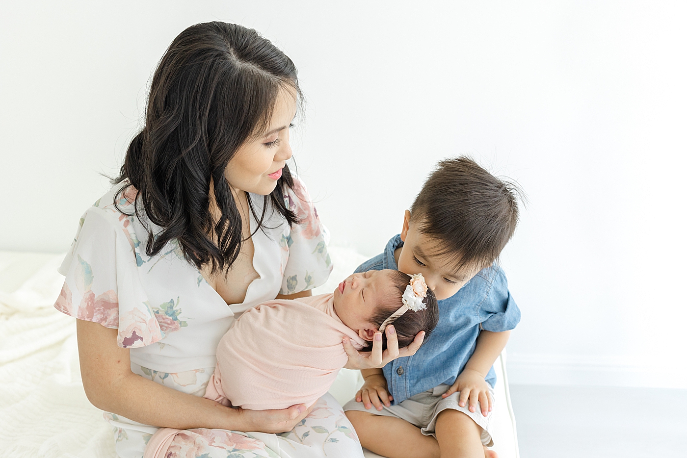 Mom and baby brother holding their new baby during her Newborn sessions with siblings | Image by Sana Ahmed