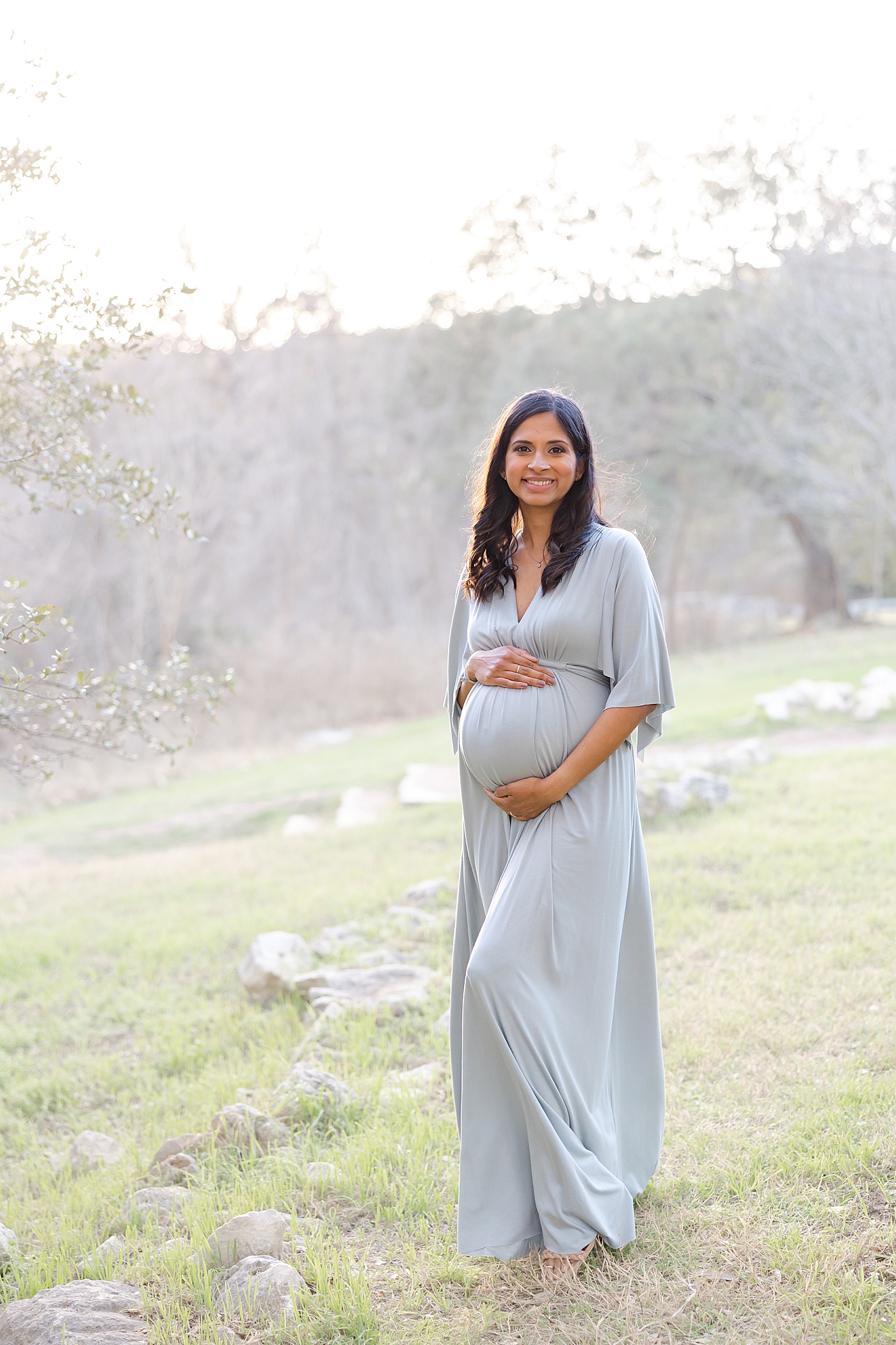 Mom to be in a blue dress holding her belly during their Austin Maternity Session| Images by Sana Ahmed 