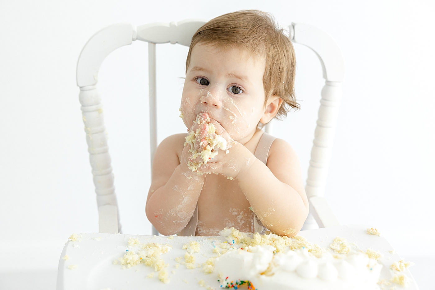 Baby boy eating cake in a white highchair | Image by Sana Ahmed