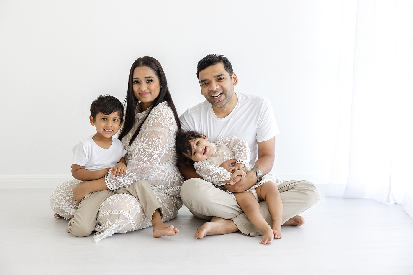 Family of four sitting on the studio floor with a white background | Image by Sana Ahmed