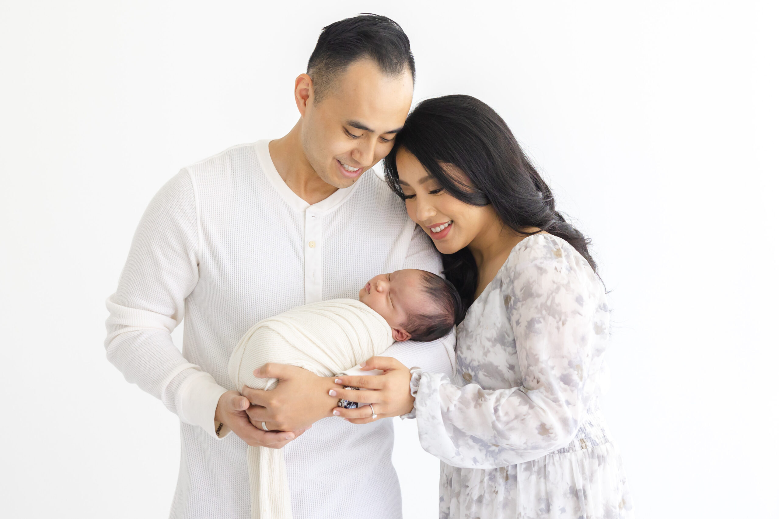 Mom and dad holding their new baby during their Precious Austin Studio Newborn Session | Image by Sana Ahmed